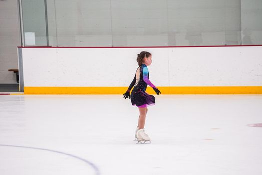 Little girl practicing before her figure skating competition at the indoor ice rink.