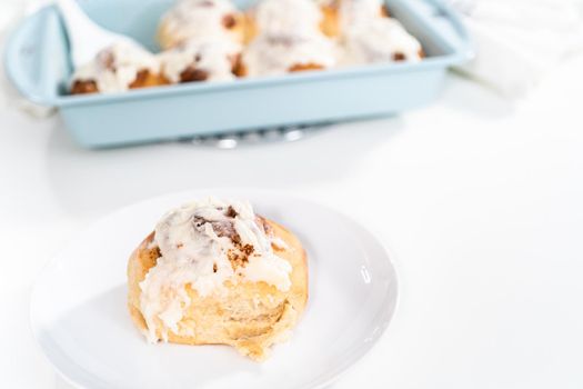 Freshly baked cinnamon rolls with white icing in a blue baking pan.