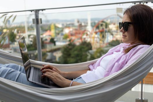 young woman freelancer working in hammock on the terrace. High quality photo