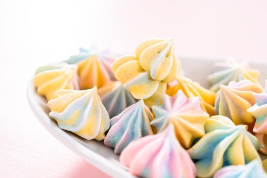 Multicolored unicorn meringue cookies on a white serving plate.