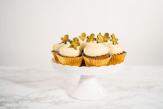Freshly baked gingerbread cupcakes with eggnog buttercream frosting and topped with a gingerbread man.