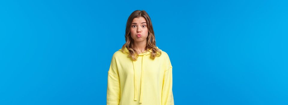 Silly and cute blond female pouting, hold her breath as promise being silent, dont tell anyone what happened or hiding secret, standing blue background, cant say anything.