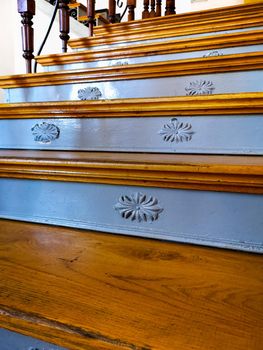 Old renovated wooden stairs with decorative steel reliefs on steps