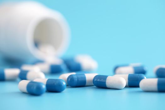 pills capsules with bottle isolated on blue background