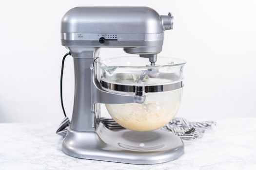 Mixing ingredients in kitchen mixer to bake homemade brioche buns.