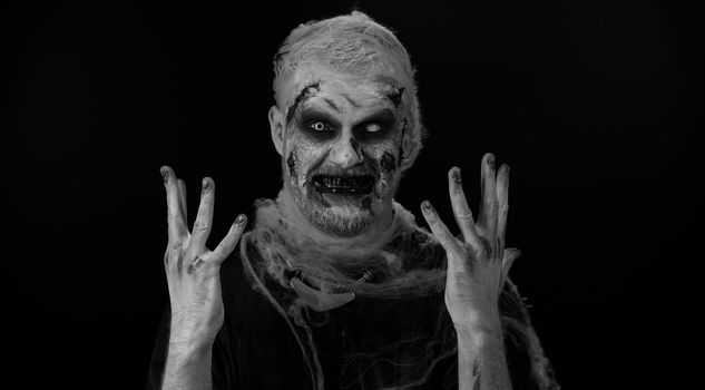 Sinister man horrible scary Halloween zombie listening music dancing disco fooling around having fun expressive gesticulating hands. Dead guy alone with wounded bloody scars face on black background
