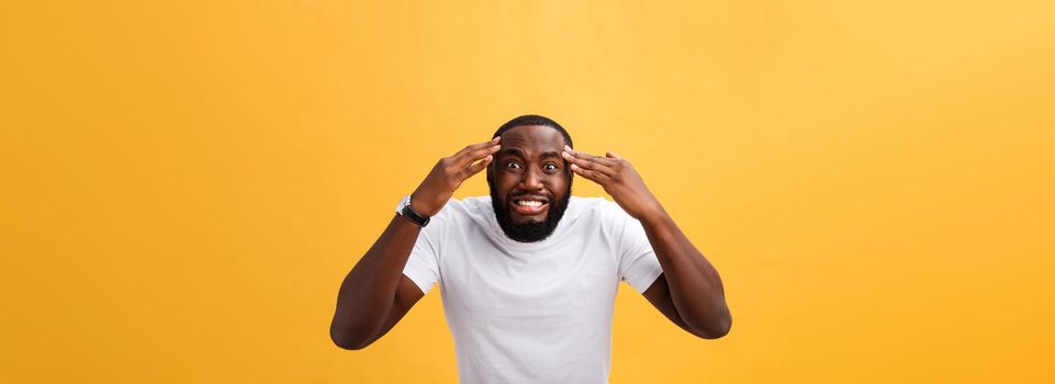 Portrait of african american man with hands raised in shock and disbelief. Isolated over yellow background