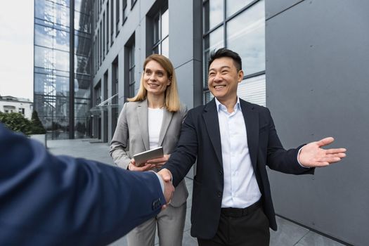 Men in business suits greet and shake hands, team of diverse business people meet outside office building