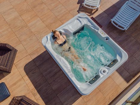 Drone view. Portrait of young carefree happy smiling woman relaxing at hot tub during enjoying happy traveling moment vacation life against the background of green big mountains.