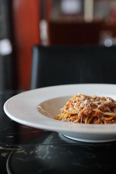 spaghetti Bolognese with minced beef and tomato sauce garnished with parmesan cheese and basil , Italian food