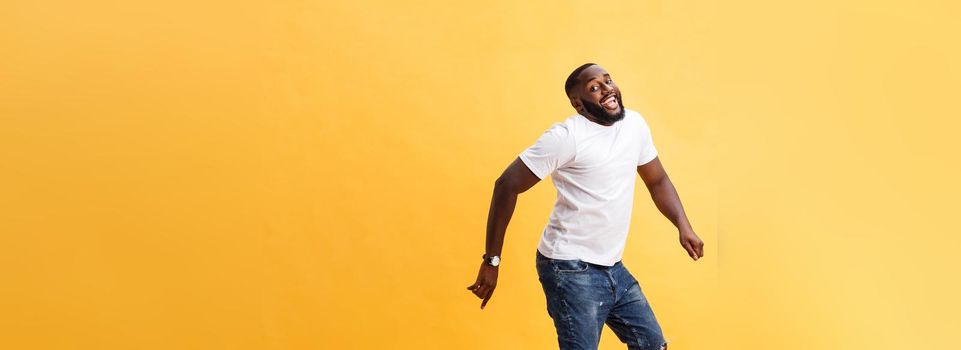 Full length of handsome young black man jumping against yellow background