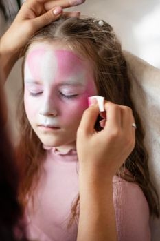 Master making aqua makeup on girl face. animator artist draws painting face art on birthday party. Child with funny face art. Children holiday, event, entertainment. Woman doing aqua makeup for girl