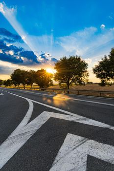 Beautiful shining sun behind trees at sunset over street