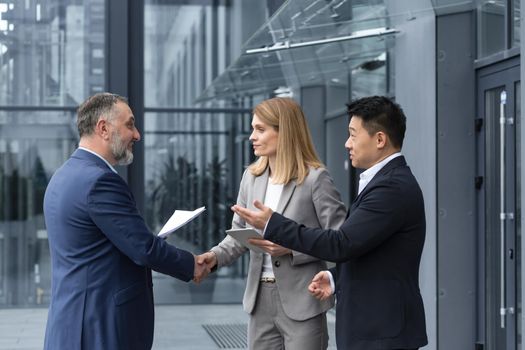 Three experienced managers team leaders, meet and get to know from outside the office team, diverse group of entrepreneurs shake hands men, introduce new colleague