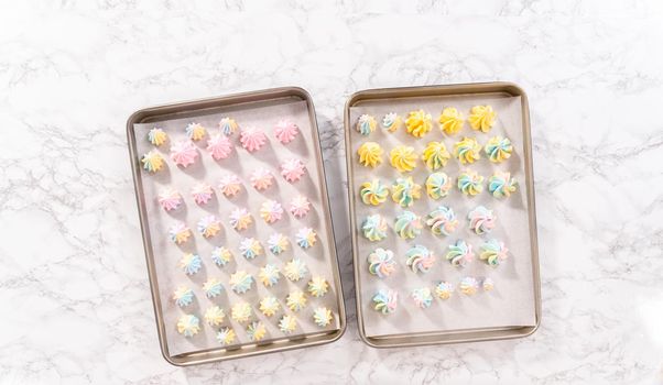 Flat lay. Unbaked unicorn meringue cookies on a baking sheet with a parchment paper.