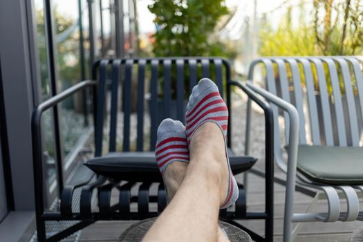 male legs in short socks stretched on the terrace. High quality photo