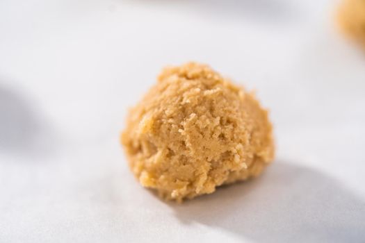 Scooping cookie dough with dough scoop into a baking sheet lined with parchment paper to bake eggnog cookies with a chocolate gingerbread man.