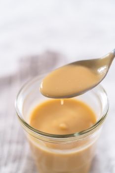 Homemade toffee glaze in a glass jar on the kitchen counter.