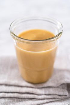 Homemade toffee glaze in a glass jar on the kitchen counter.