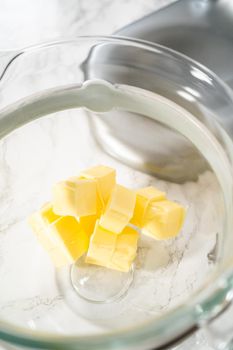 Mixing ingredients in a large glass mixing bowl of kitchen mixer to make eggnog buttercream frosting.