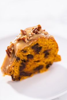 Slice of homemade chocolate pumpkin bundt cake with toffee glaze on a plate.