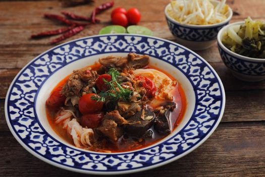 Local northern thai food Rice noodles with pork in spicy soup in wood background