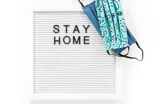 STAY HOME sign on message board with a homemade face mask.