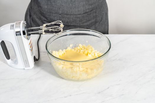 Mixing ingredients in a large glass mixing bowl to bake red velvet bundt cake with cream cheese glaze.