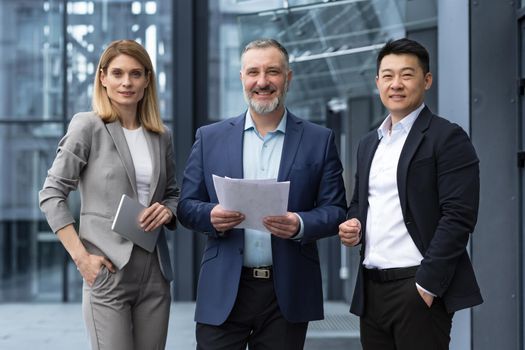 Successful mature business team man and woman businessmen in business suits smiling and looking at camera outside office building and specialist investors team smiling and happy
