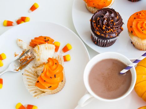 Eating Halloween cupcakes with orange and black icing.