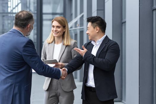 Three experienced managers team leaders, meet and get to know from outside the office team, diverse group of entrepreneurs shake hands men, introduce new colleague