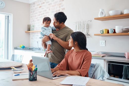 Family, baby and down syndrome while mother work online with laptop in kitchen. Mom, father and child play while mother use computer for learning, education or college on the internet in house.