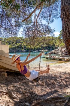Woman on a swing on the shore of a Mediterranean cove
