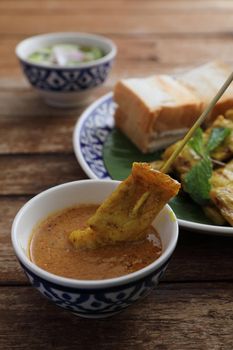 Local Thai food pork satay with oeanut dipping sauce isolated in wood background
