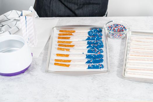 Dipping pretzel rods into the melted chocolate to prepare chocolate dipped pretzel rods for the July 4th celebration.