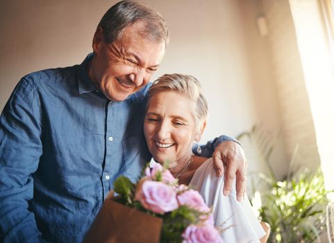 Couple, romance and flowers with a senior man and woman in celebration of valentines day or their anniversary. Retirement, love and affection with an elderly male and female pensioner in their home.
