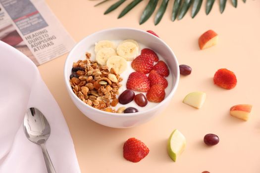 bowl of granola cereal with yogurt and berries isolated on eggnog color background