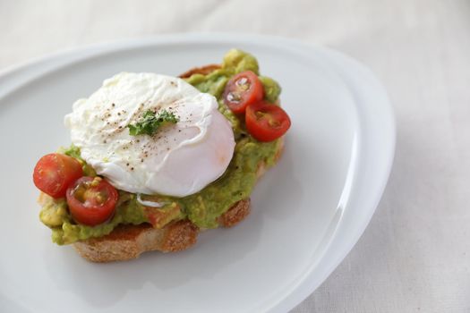 Poached eggs with avocado on toast in white background