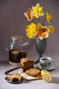 Still life, concept of early spring breakfast with coffee or tea and cupcake on the background of a bouquet of tulips and daffodils