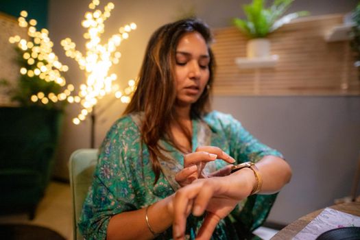 indian woman at the restaurant using smartwatch