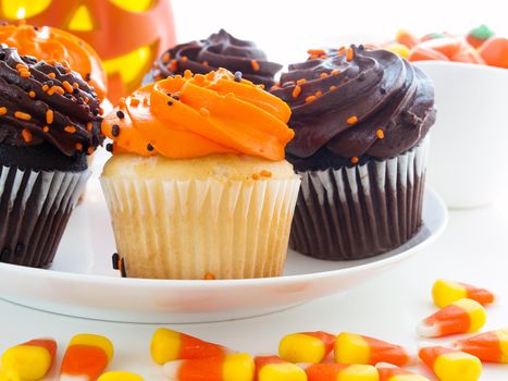 Halloween cupcakes with orange and black icing on white plate.