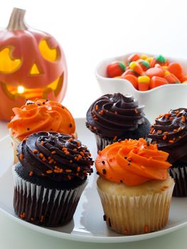 Halloween cupcakes with orange and black icing on white plate.