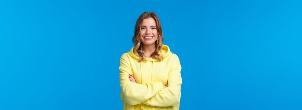 Lets get business. Confident smiling cheerful blond woman with white perfect smile, cross hands chest ready for tasks, listen to boss instructions, standing yellow hoodie over blue background.