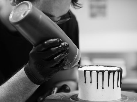 unrecognizable worker preparing a sweet dripping choco cake and berries