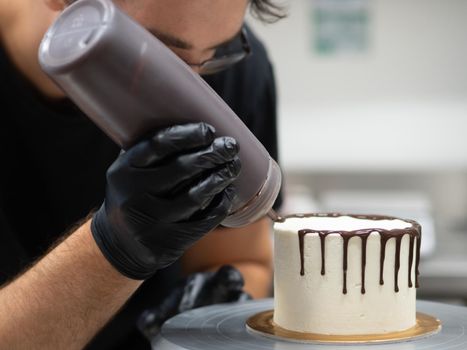unrecognizable worker preparing a sweet dripping choco cake and berries