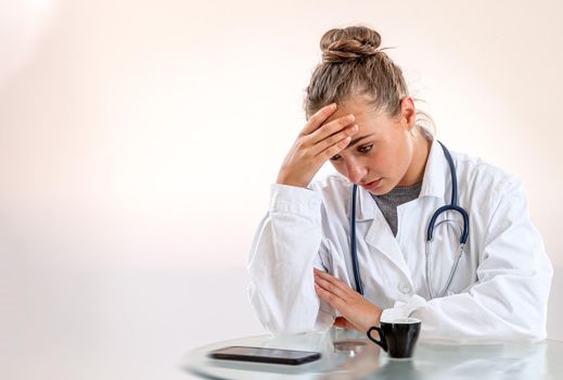 Young woman in exhausted pose in front of her cup of coffee