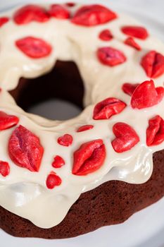 Freshly baked red velvet bundt cake with chocolate lips and hearts over cream cheese glaze for Valentine's Day.