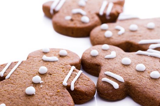 Homemade gingerbread cookies decorated with white icing on white background.