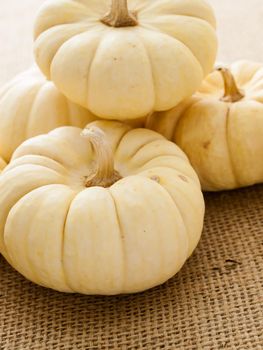 Small white pumpkins on burlap fabric.