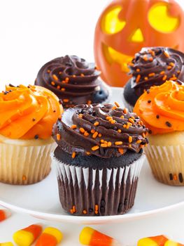 Halloween cupcakes with orange and black icing on white plate.